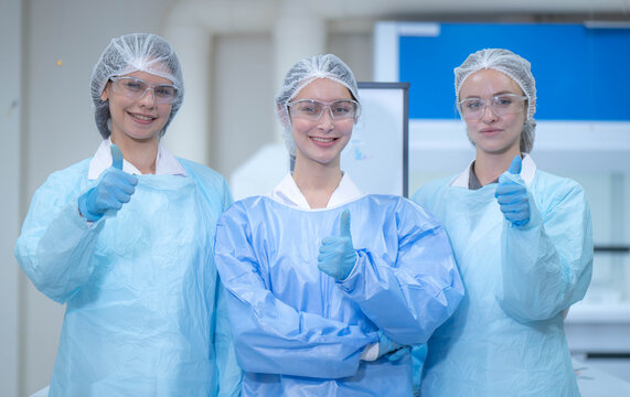 Portrait of three female laboratory researchers standing confidently together in protective clothing