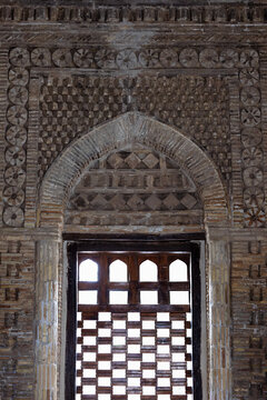 Ornamental brickwork and wooden lattice window of the Samanid Mausoleum in Bukhara, Uzbekistan. Detailed facade showing geometric patterns and pointed arch, ideal for architecture and heritage.
