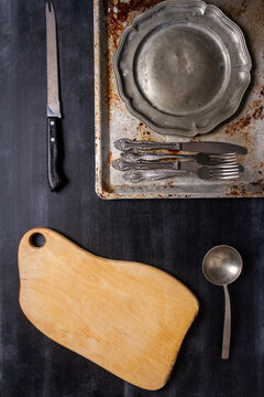 Old various kitchen utensils on black chalkboard background. Food themed flat lay.