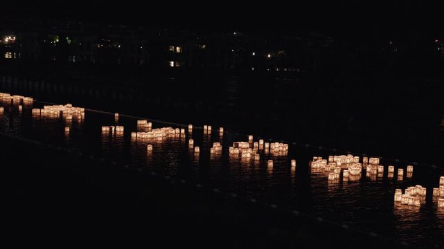 Elevated View of Floating Paper Lanterns Clustered on Dark River at Night