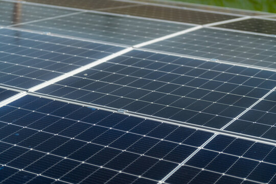Rows of polycrystalline photovoltaic modules run away in sharp perspective across a factory roof, with no people in frame - a clean background image for renewable energy design.