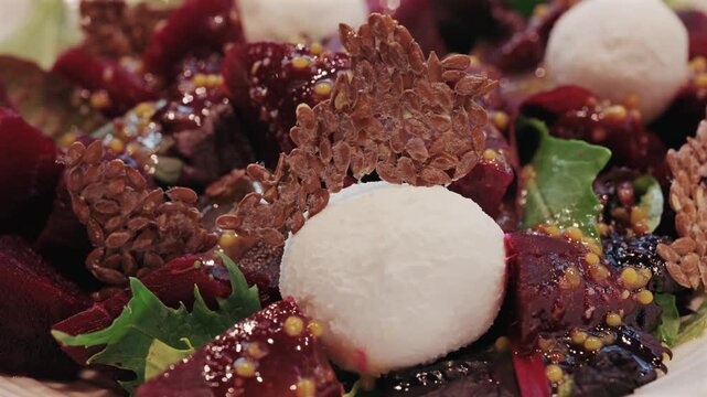 Fresh beet salad with mozzarella cheese balls and flaxseed crackers served on white plate.