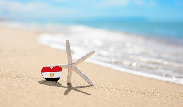 Starfish and Egypt flag on sandy beach.