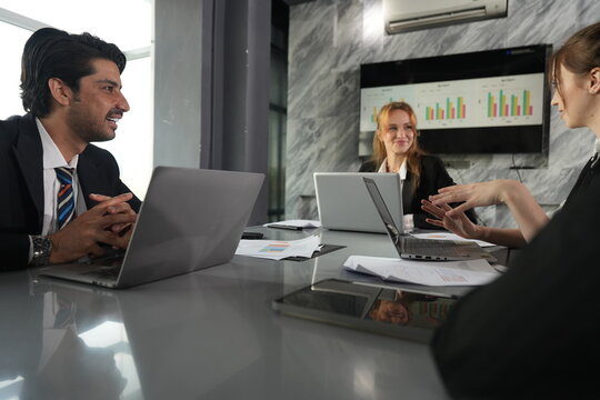 Hand stretched across the table, the young analyst presses her point as the manager chuckles behind his laptop in the sunlit meeting room in a bright modern coworking office.