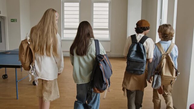 Group of Caucasian teenagers with backpacks walking through school gym, tracking shot. Footage is ideal for educational marketing and school promos