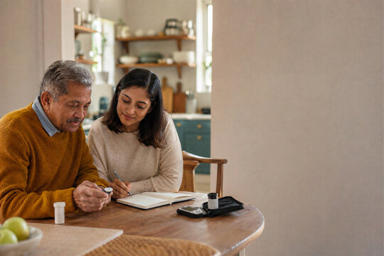 Senior man and adult daughter reviewing diabetes readings together at home