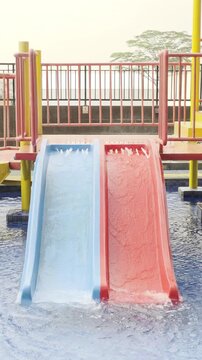 A colourful children's water playground (splash park) located in an outdoor swimming pool, situated on a rooftop setting with a modern glass-walled building in the background.