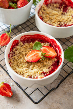 Traditional English crumble cake with strawberry with backed topping  of oatmeal flour, butter and sugar in a baking dish on a stone countertop.