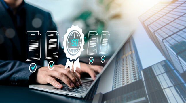 Businessman typing on laptop with digital ISO certification badge and approved documents. Concept of quality management system, international standard compliance, and corporate quality assurance.