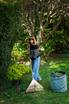 Mid-aged woman cleaning the backyard from leaves