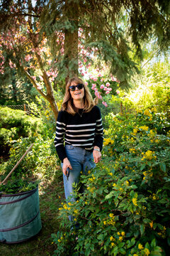 Mid-aged woman and removing old stems and leaves in a back yard