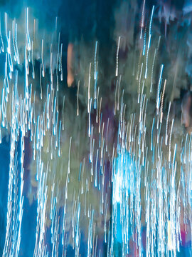 Abstract long exposure neon light trails creating a dynamic motion blur background with vertical glowing streaks.