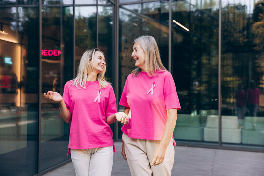 Portrait of two smiling happy women, senior and young wearing stylish pink t shirt with ribbon