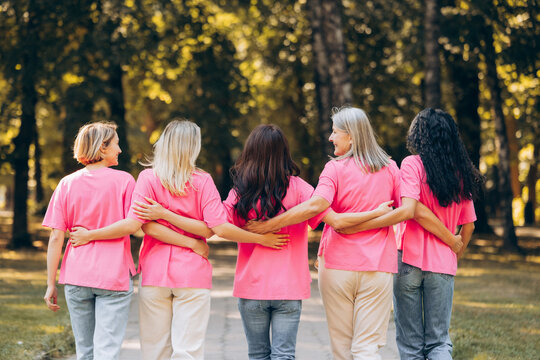 Back view diverse group of multinational women wearing stylish pink t shirts hugging together