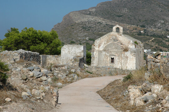 Traditional historic stone church of Agios Ioannis Prodromos stands at the end of a concrete path surrounded by ancient ruins and rocky hillsides inside Chora fortress on Kythira island