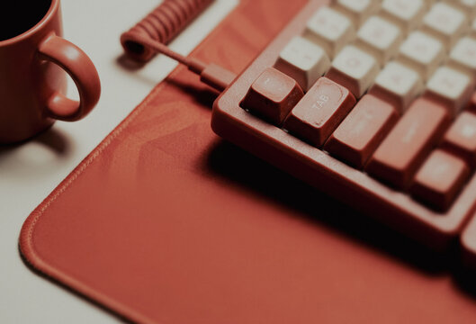 Red mechanical keyboard with white keycaps and coffee cup