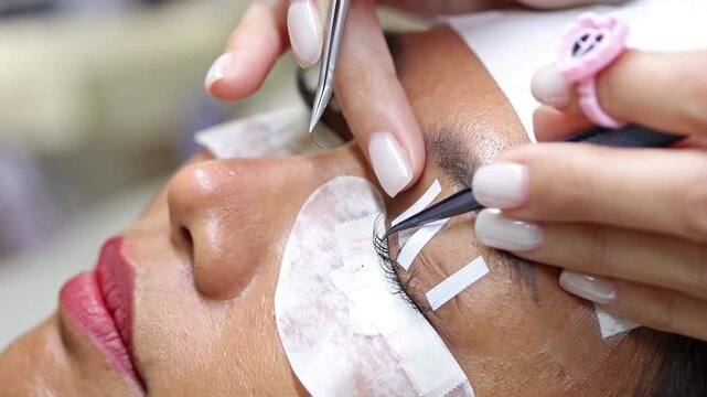 The process of eyelash extension and volume increase in a professional beauty salon, close-up view