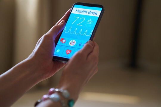 Woman holds smartphone with health tracker app indoors