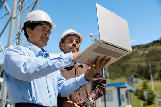 Engineers check data on a laptop at an outdoor electricity substation