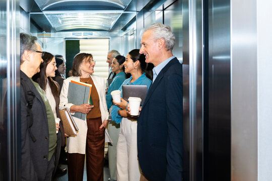 Smiling business colleagues share a conversation inside an elevator