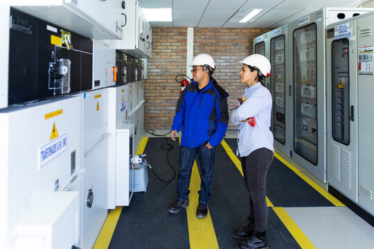 A man and woman inspect an electrical control box at a wind farm