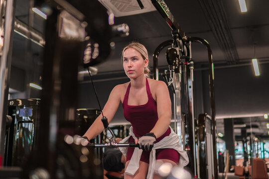 Woman does strength training on a cable machine in the gym