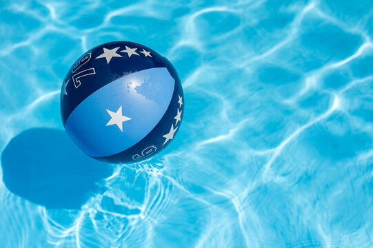 Beachball floatig in a swimmingpool on a bright sunny day