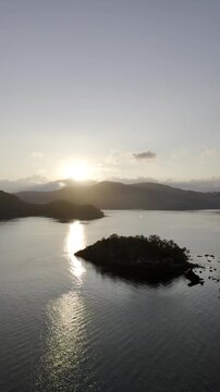 Aerial drone view of Calm waters of Pangulatan with an island beyond the shore at sunrise