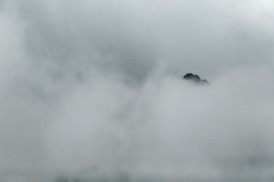 Minimalist Silhouette of a Mountain Peak in Dense White Fog