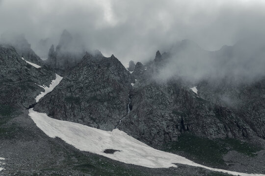 Dark Jagged Spires With a Hidden Waterfall in a Misty Gorge
