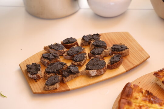Canap&eacute;s de tapenade d&rsquo;olives noires servis sur une planche en bois