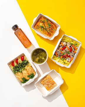 Healthy balanced food delivery ration with farfalle pasta mushrooms chicken cutlets green soup casserole and tea on yellow and white background