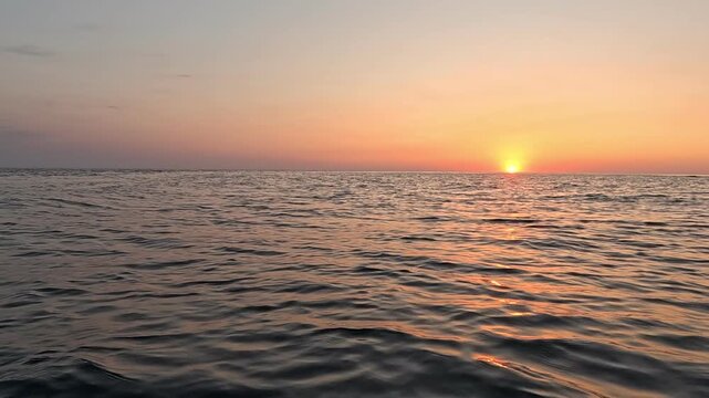 Vibrant sunset glowing on ocean water waves during peaceful evening twilight. Panning shot.