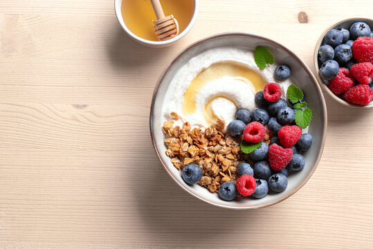 Granola bowl with greek yogurt, berries and honey for healthy breakfast.