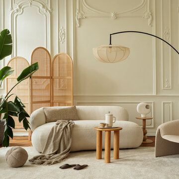 Elegant and cozy modern living room interior design with neutral cream color palette, comfortable curved sofa, stylish furniture, and warm lighting