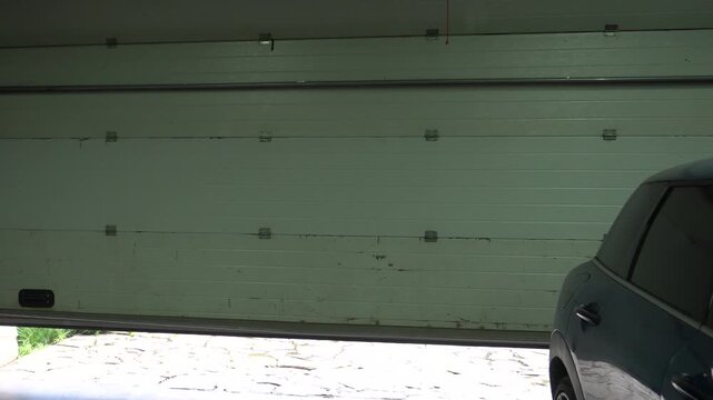 Closing of sectional garage doors. White garage lift door. Garage door inside.