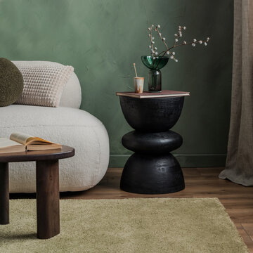 Modern interior design with green wall, white sofa, black side table, glass vase, book, rug, and cozy living room atmosphere for home decor