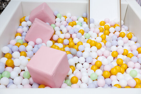 Children's pastel ball pit with soft cubes in indoor nursery play area