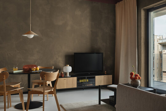 Modern minimalist living room interior design with neutral earth tones, wooden furniture, dining table, television, and large window view daylight