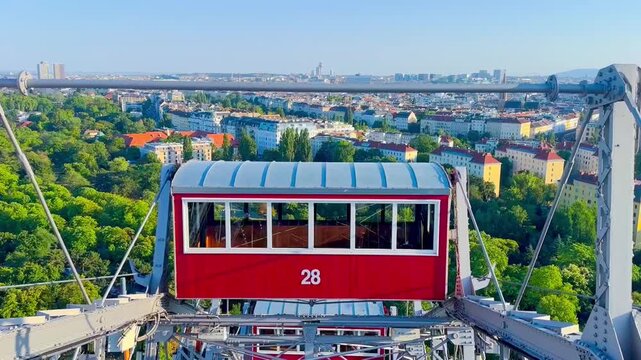 High-angle view of red cabin number 28 on the Wiener Riesenrad Giant Ferris Wheel with panoramic cityscape of Vienna in the background