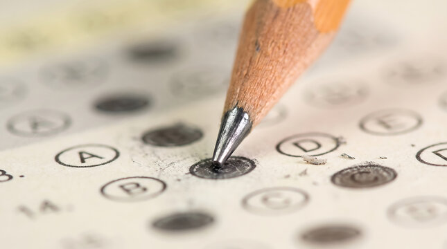 Detailed close-up view of a pencil marking the correct answer circle on an examination test form with exam form test sheet multiple choice exam paper questionnaire