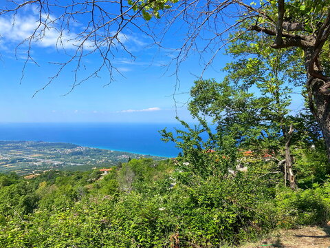 Unsurpassed panorama from the thickets of the mountain forest of the lush blue of the Aegean Sea on the horizon with coastal settlements on the slopes of the mountain hills.