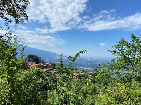 Panorama of mountain ranges in curly clouds descending to the sea coast in the rays of the summer sun.