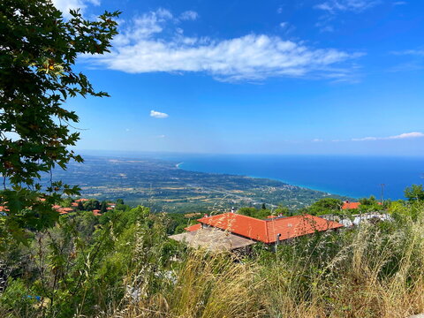 Unsurpassed panorama from the thickets of the mountain forest of the lush blue of the Aegean Sea on the horizon with coastal settlements on the slopes of the mountain hills.