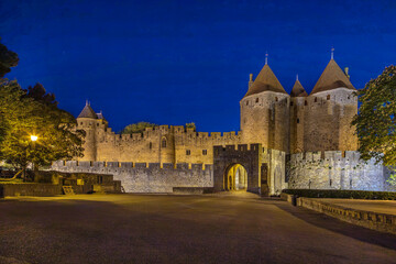 Fototapeta premium Evening view of Cite de Carcassonne in France, showing the illuminated main entrance. Medieval fortress architecture at dusk
