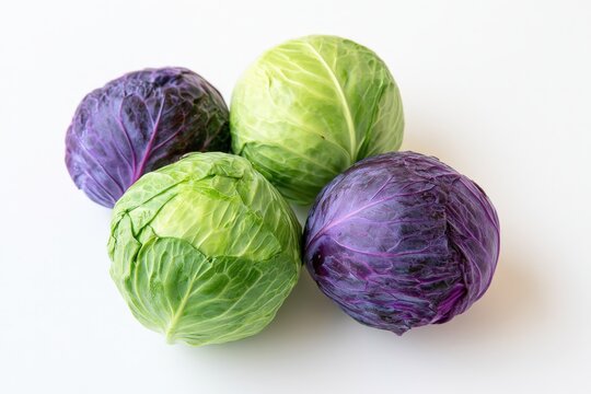 Four cabbage heads rest on a bright white surface