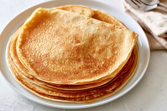 Golden pancakes stack neatly on a white plate