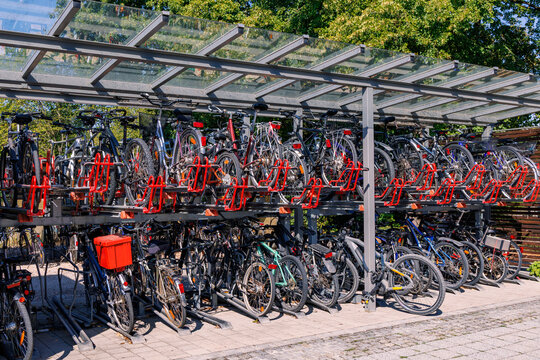 Two tier bicycle parking rack filled with bikes under glass shelter, sustainable urban transport and cycling infrastructure concept