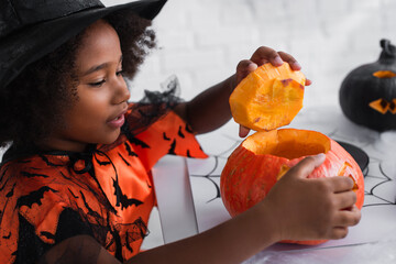 Fototapeta premium Little girl enjoys creating a spooky pumpkin design for Halloween celebration