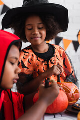 Fototapeta premium Adorable siblings enjoy Halloween festivities while carving pumpkins together